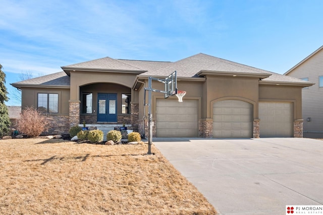 prairie-style home with a garage, stone siding, french doors, concrete driveway, and stucco siding