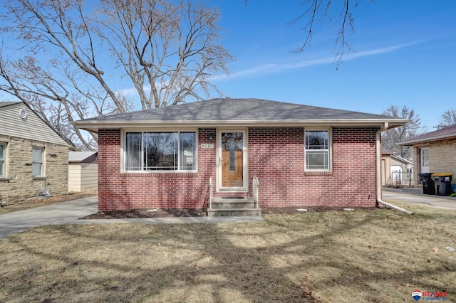 bungalow-style house with a front yard, brick siding, and roof with shingles