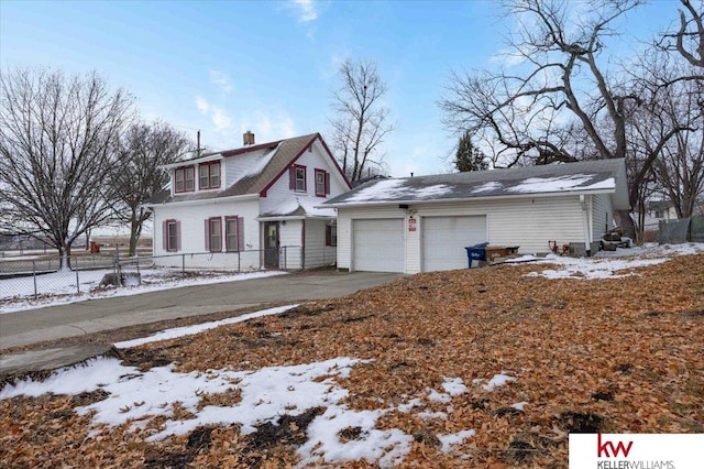 view of front facade featuring driveway, fence, and a chimney