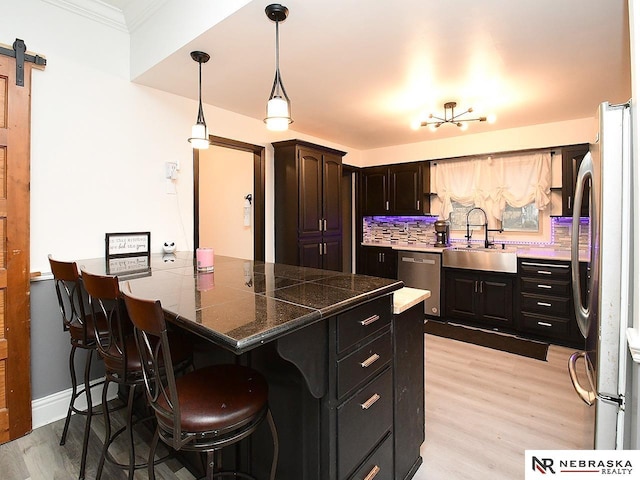 kitchen with stainless steel appliances, a barn door, a sink, a peninsula, and a kitchen bar