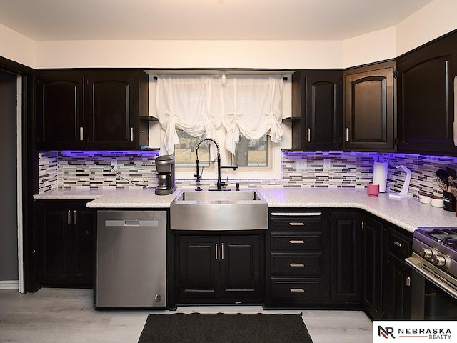 kitchen featuring stainless steel appliances, light countertops, backsplash, light wood-style floors, and a sink