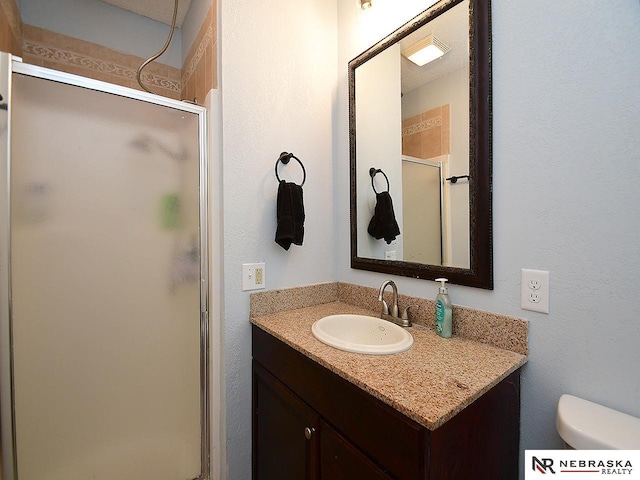 bathroom featuring toilet, a shower stall, and vanity