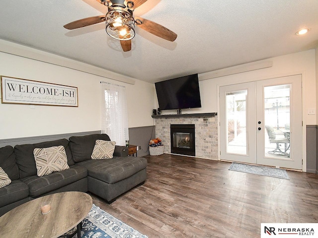 living room with a textured ceiling, a fireplace, wood finished floors, and french doors