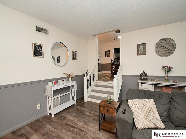 living area with a ceiling fan, a textured ceiling, visible vents, and wood finished floors