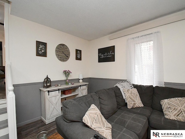 living room featuring dark wood-style floors, a textured ceiling, and wainscoting