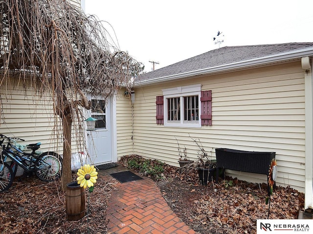 doorway to property featuring roof with shingles