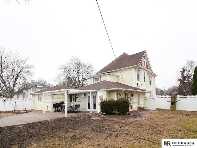 rear view of house featuring a garage, concrete driveway, a patio, a fenced backyard, and french doors