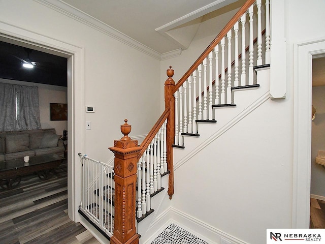 stairway featuring ornamental molding, baseboards, and wood finished floors