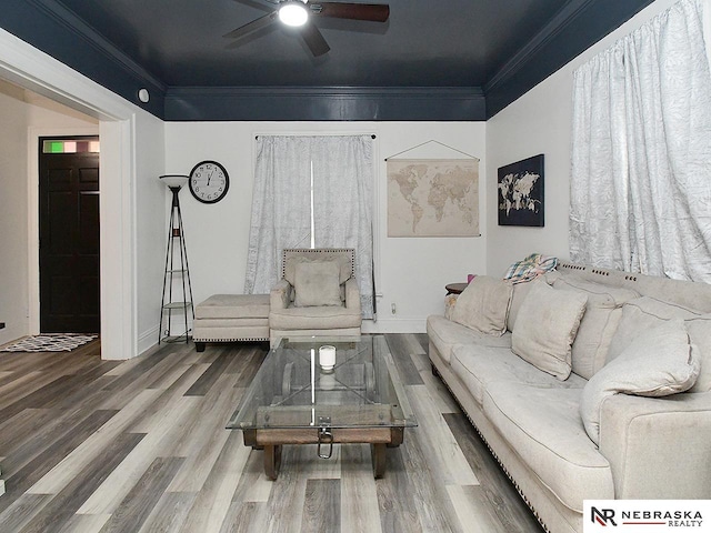 living area featuring a ceiling fan, baseboards, ornamental molding, and wood finished floors