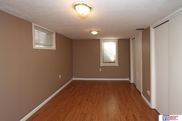 unfurnished bedroom with a textured ceiling, wood finished floors, visible vents, and baseboards