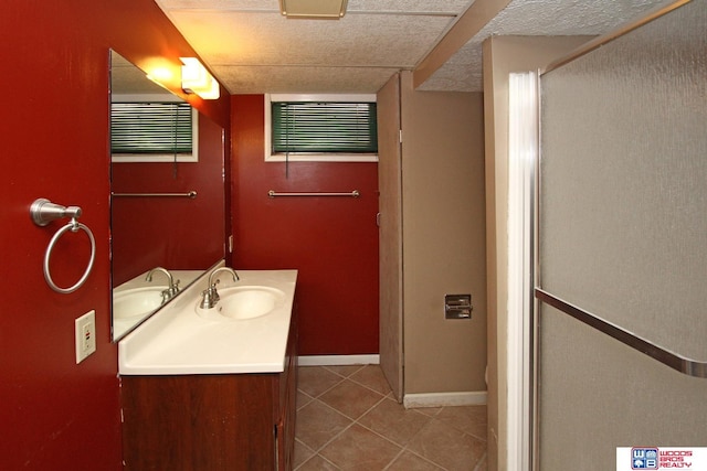 full bathroom with a textured ceiling, tile patterned flooring, vanity, baseboards, and an enclosed shower