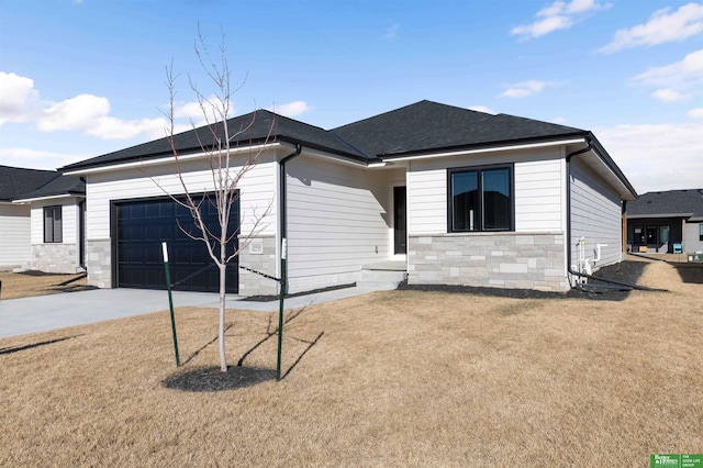 view of front of house with driveway, a shingled roof, stone siding, an attached garage, and a front lawn