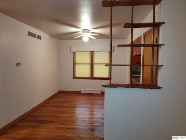 unfurnished room with a ceiling fan, visible vents, baseboards, and wood finished floors