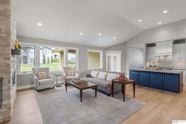 living area featuring lofted ceiling, recessed lighting, a fireplace, baseboards, and light wood-type flooring