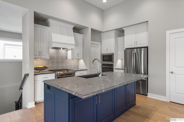 kitchen with stainless steel appliances, a sink, white cabinetry, and light wood-style floors