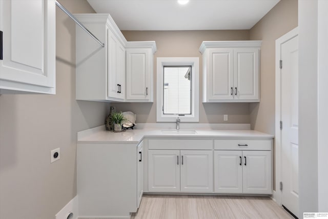 kitchen featuring light countertops, a sink, and white cabinetry