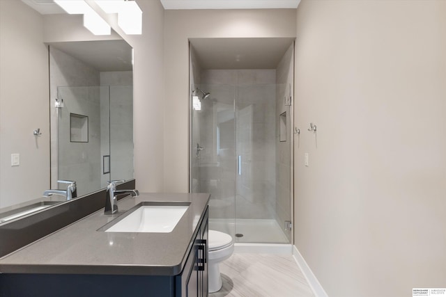 bathroom featuring baseboards, a shower stall, toilet, and vanity