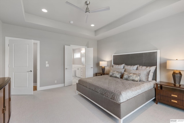 carpeted bedroom featuring a tray ceiling, recessed lighting, a ceiling fan, ensuite bath, and baseboards