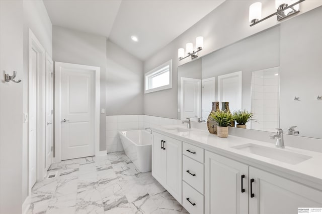 full bathroom featuring a freestanding bath, double vanity, a sink, and lofted ceiling