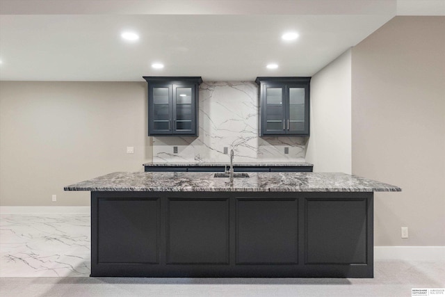 kitchen with marble finish floor, recessed lighting, backsplash, a sink, and light stone countertops