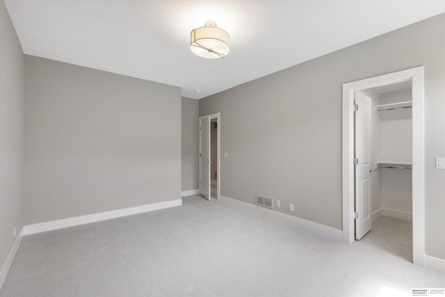 unfurnished bedroom with carpet flooring, visible vents, baseboards, a spacious closet, and a closet