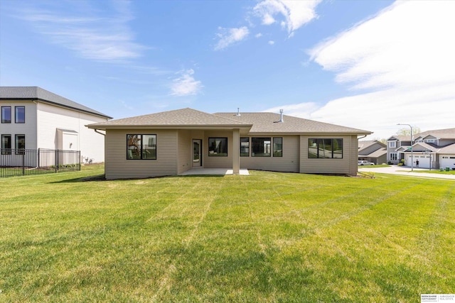 rear view of property featuring a patio area, fence, and a lawn