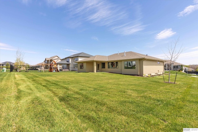 back of property featuring a playground, a residential view, and a lawn