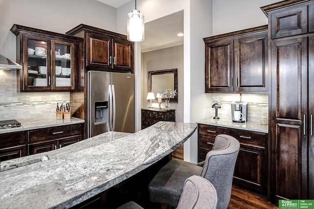 kitchen with appliances with stainless steel finishes, decorative backsplash, light stone counters, and a kitchen breakfast bar