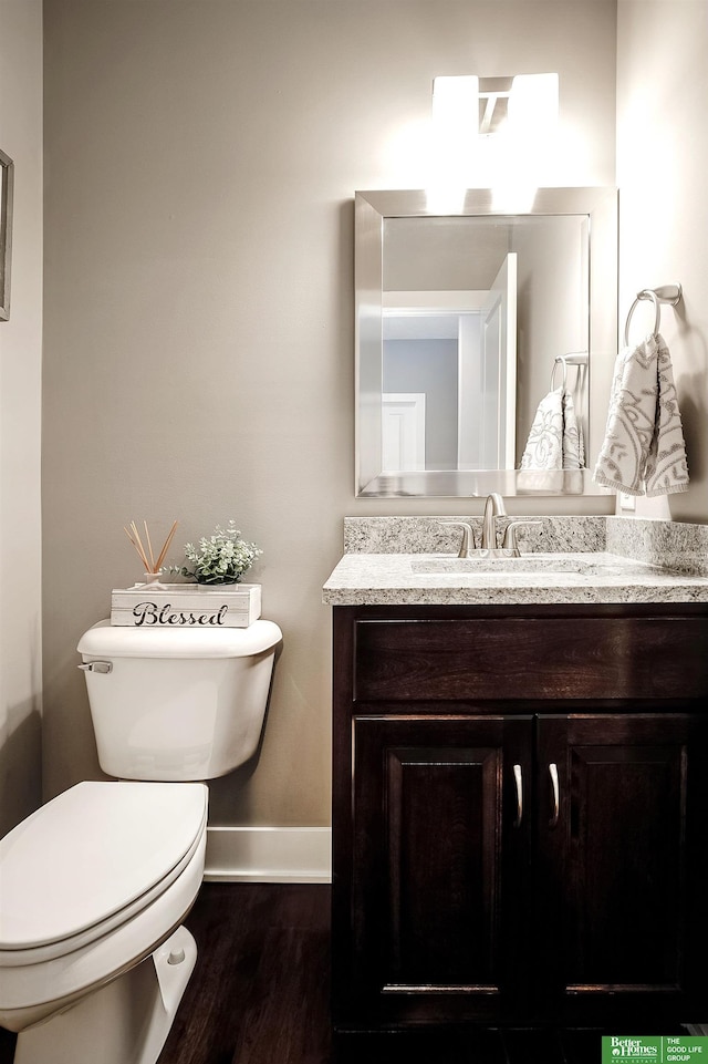 bathroom featuring toilet, baseboards, wood finished floors, and vanity