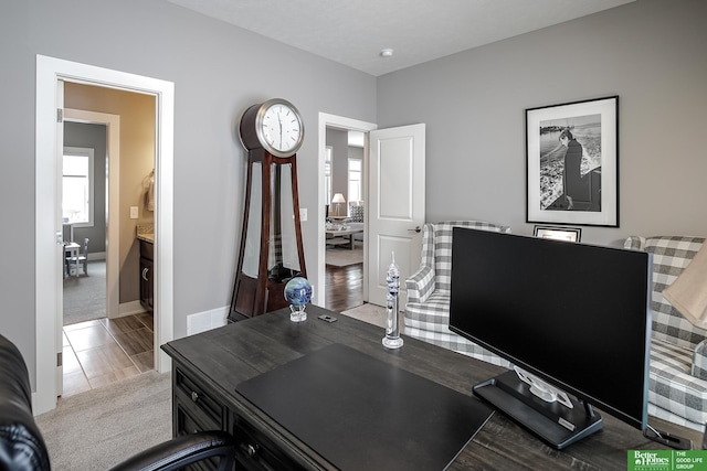 office with light colored carpet, light wood-type flooring, visible vents, and baseboards