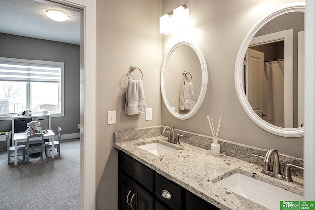 full bathroom featuring double vanity, baseboards, and a sink