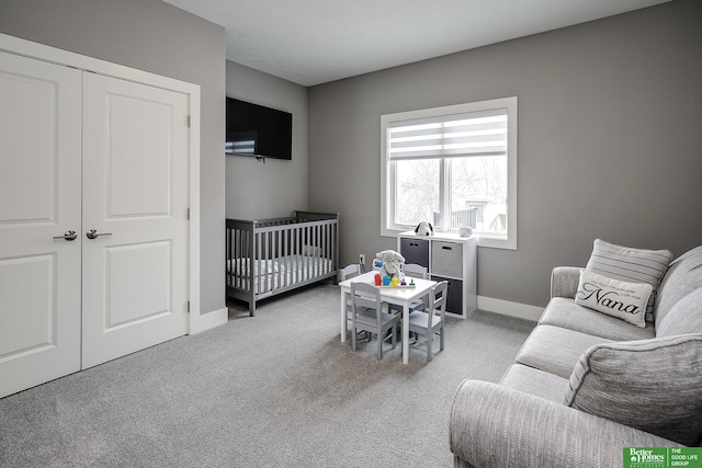 bedroom with baseboards, a crib, a closet, and light colored carpet