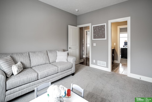 living room with carpet floors, visible vents, and baseboards