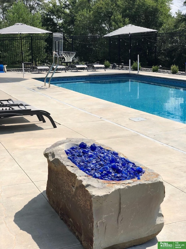 community pool with a patio and fence