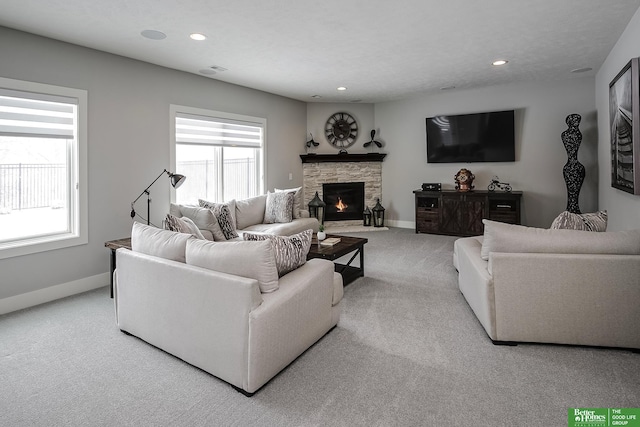 living area featuring baseboards, recessed lighting, a fireplace, and a healthy amount of sunlight