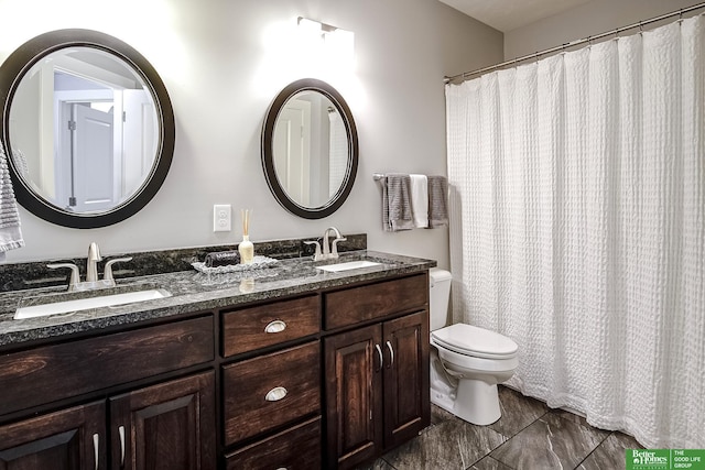 bathroom featuring double vanity, a sink, and toilet