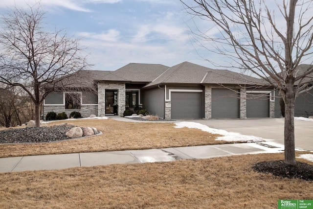 prairie-style home with driveway, a shingled roof, stone siding, an attached garage, and a front lawn