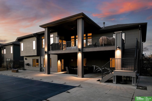 back of property at dusk featuring stairs, fence, a fenced in pool, and a patio