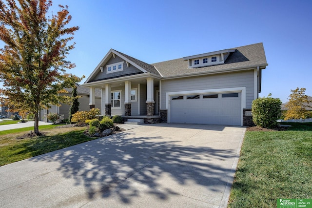 view of front of property with covered porch, a front yard, a garage, stone siding, and driveway