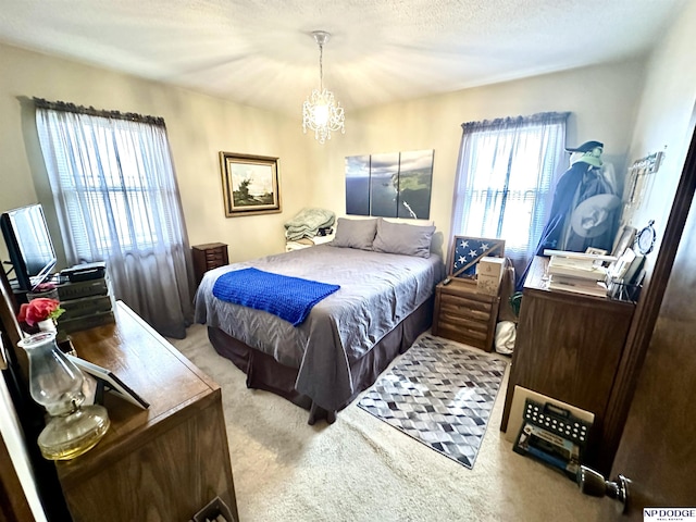 bedroom featuring a chandelier, carpet, multiple windows, and a textured ceiling