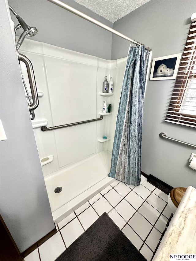 full bath featuring a shower stall, a textured ceiling, and tile patterned floors