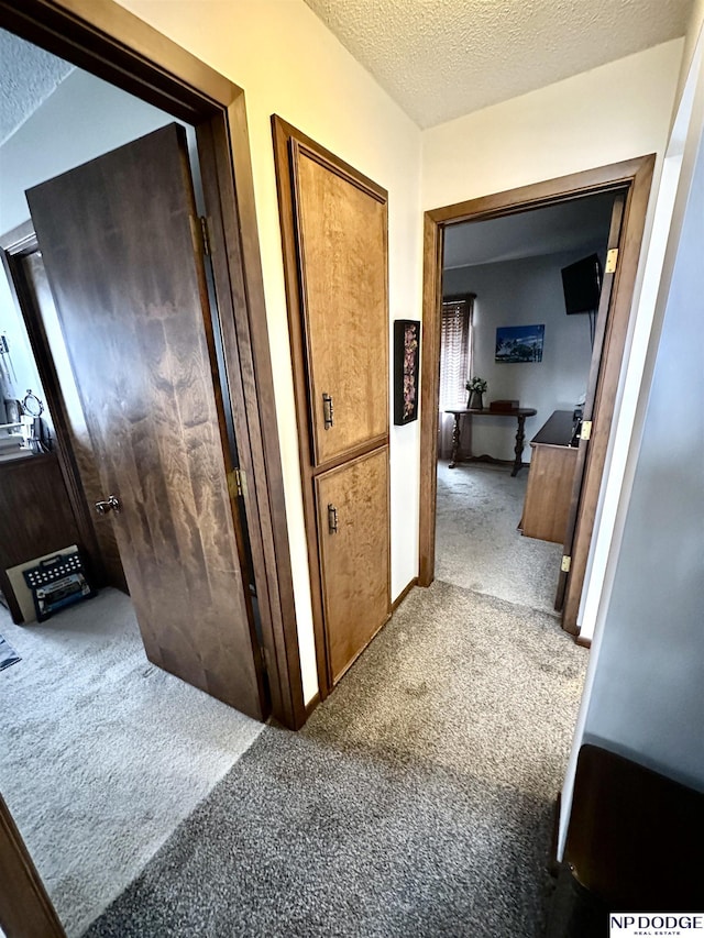 corridor with a textured ceiling and carpet flooring