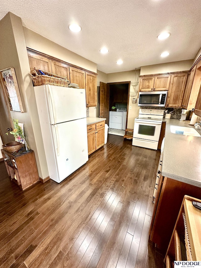 kitchen featuring dark wood-style flooring, light countertops, a sink, separate washer and dryer, and white appliances