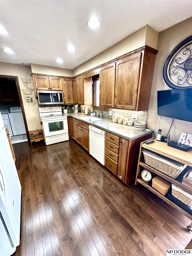 kitchen featuring brown cabinets, white appliances, dark wood finished floors, and washer and dryer