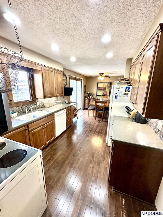 kitchen featuring dark wood-style floors, white appliances, a sink, and a healthy amount of sunlight