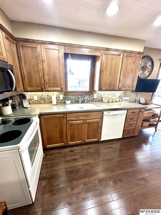 kitchen with tasteful backsplash, light countertops, dark wood-type flooring, a sink, and white appliances