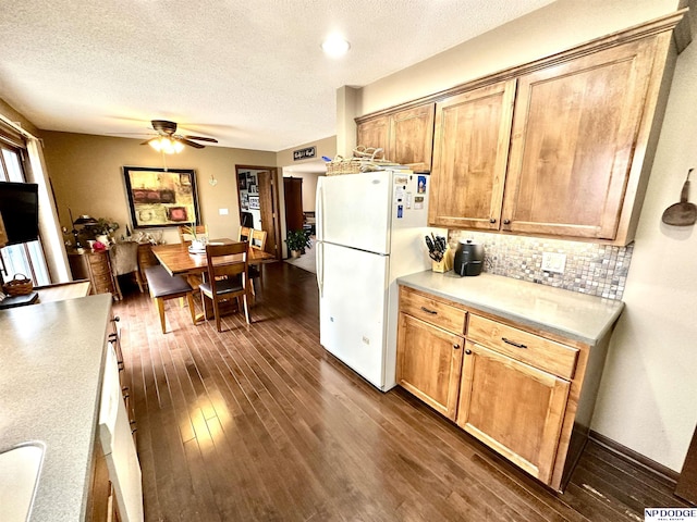 kitchen featuring a ceiling fan, light countertops, freestanding refrigerator, dark wood-style floors, and tasteful backsplash