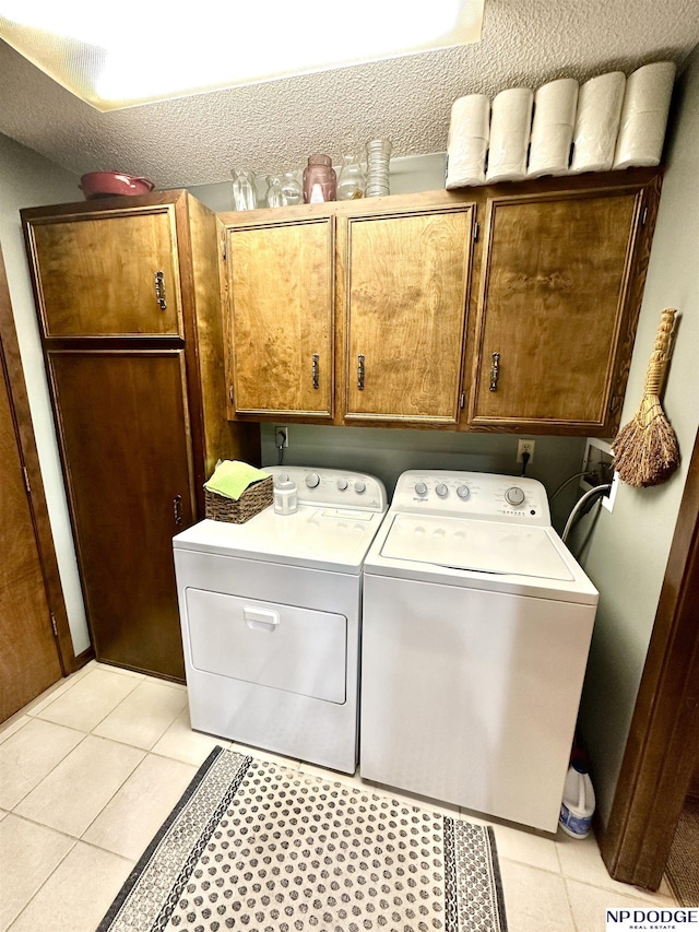 laundry room with washer and dryer, cabinet space, a textured ceiling, and light tile patterned flooring