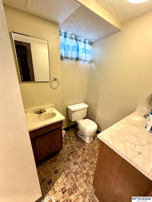 bathroom featuring toilet, a textured ceiling, and vanity