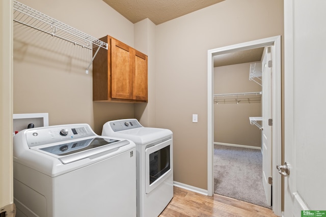 washroom with light wood-type flooring, cabinet space, baseboards, and separate washer and dryer